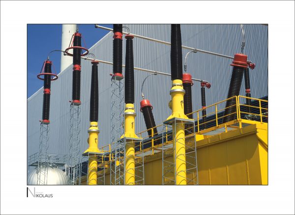 Gelbe Isolatoren vor einer Stahlfassade