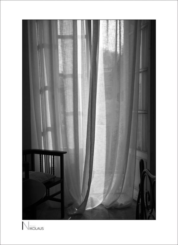 Schwarzweiss-Blick durch die Gardinen eines italienischen Landhauses